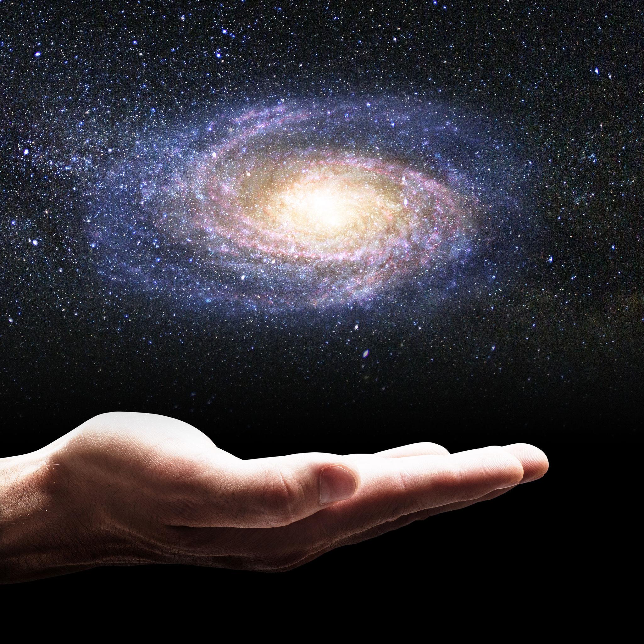 Hand holding glowing spiral galaxy in palm